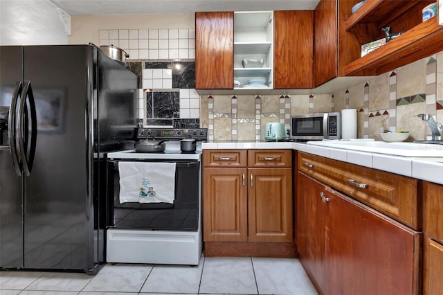 kitchen with light tile patterned floors, decorative backsplash, black refrigerator with ice dispenser, and white electric range oven