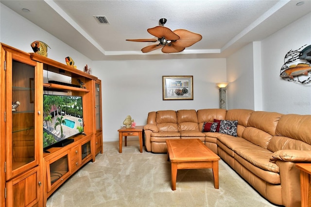 carpeted living room featuring a textured ceiling, a tray ceiling, and ceiling fan