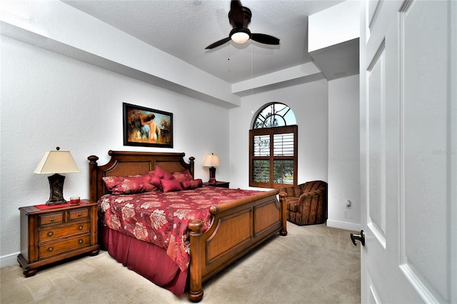 bedroom featuring ceiling fan, light colored carpet, a textured ceiling, and a closet