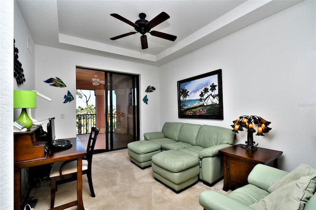 carpeted living room featuring a tray ceiling and ceiling fan