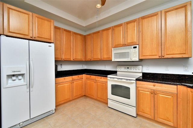 kitchen featuring light tile patterned floors, dark stone counters, and white appliances