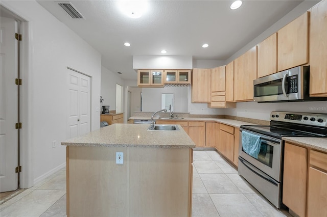 kitchen featuring sink, appliances with stainless steel finishes, a kitchen island with sink, light tile patterned flooring, and light brown cabinetry