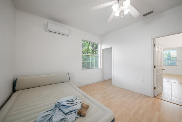 bedroom featuring ceiling fan, a wall mounted AC, and hardwood / wood-style floors