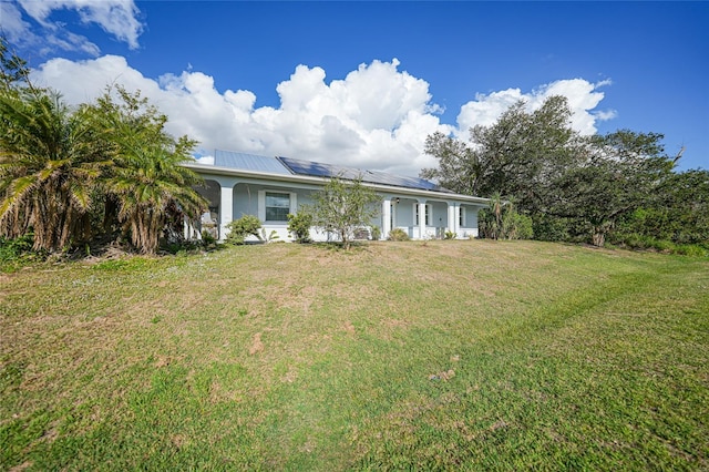 view of front of house with a front lawn and solar panels