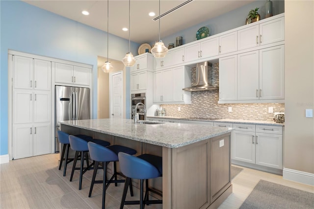 kitchen featuring white cabinetry, wall chimney exhaust hood, stainless steel appliances, and light stone counters