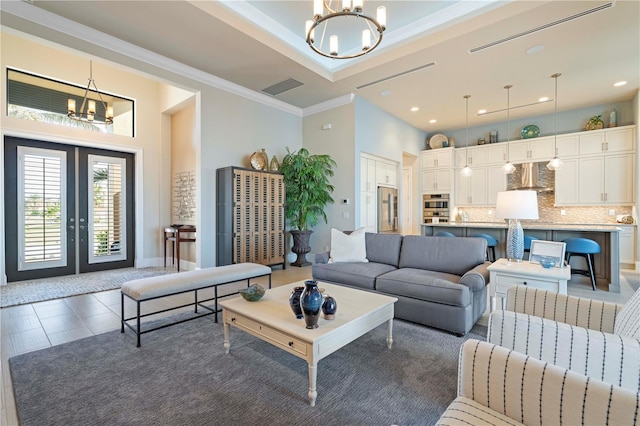 living room with french doors, an inviting chandelier, dark tile patterned flooring, and crown molding