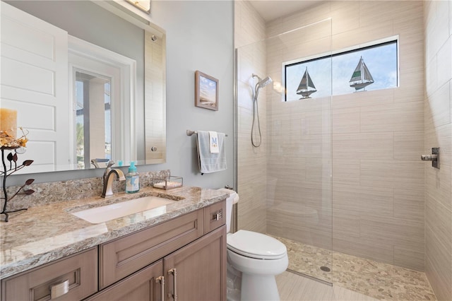 bathroom with vanity, toilet, and a tile shower