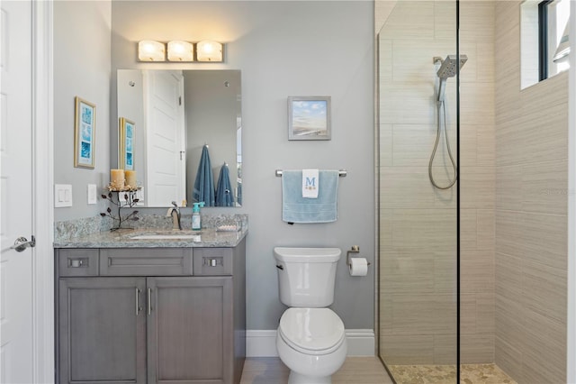 bathroom featuring a tile shower, vanity, and toilet