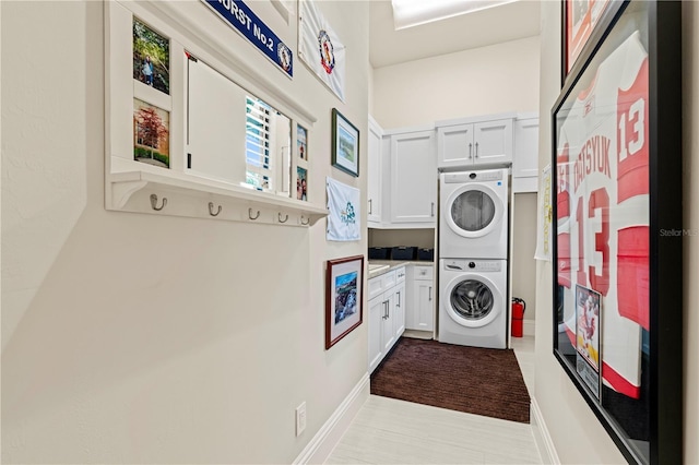 laundry room featuring stacked washer / drying machine and cabinets