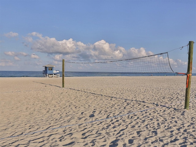 surrounding community with volleyball court, a water view, and a view of the beach