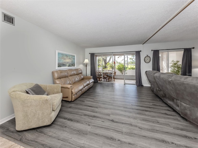 living area featuring visible vents, a textured ceiling, baseboards, and wood finished floors