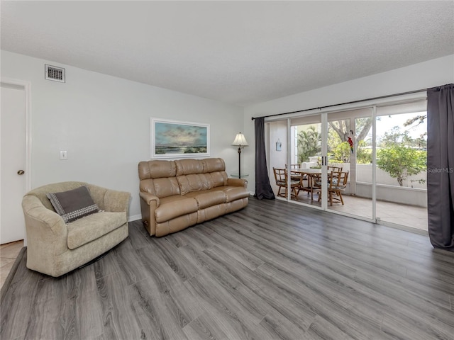 living room with a textured ceiling, visible vents, and light wood-style floors