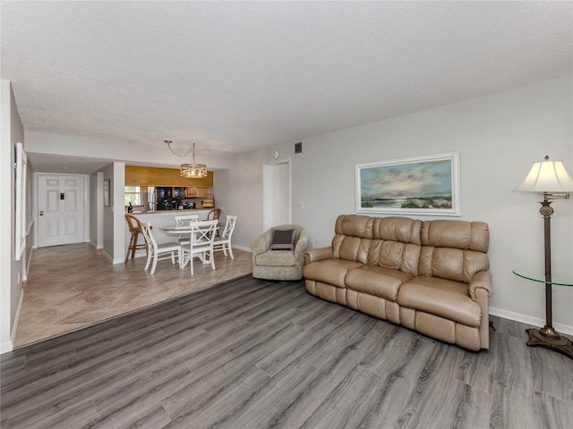 living area featuring a textured ceiling, wood finished floors, and baseboards