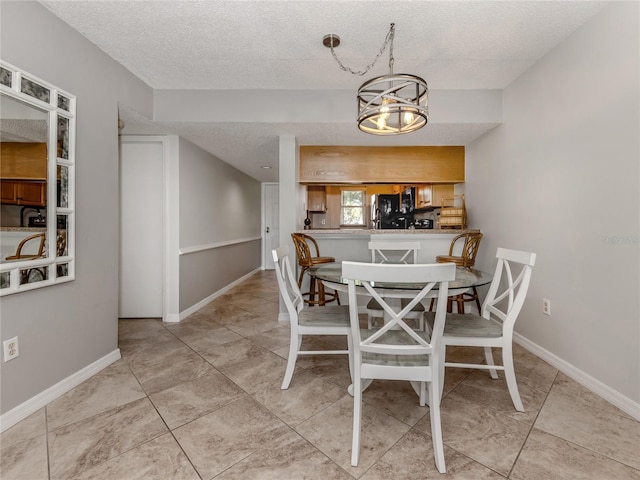 tiled dining space with baseboards and a textured ceiling