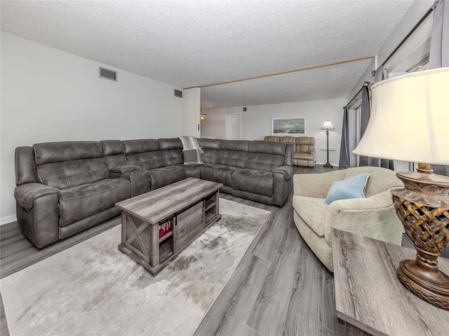 living area with light wood-type flooring, visible vents, and a textured ceiling