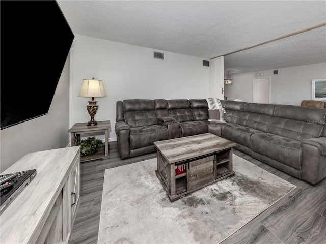 living area featuring light wood-type flooring, visible vents, and a textured ceiling