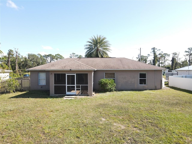 back of property with a lawn and a sunroom