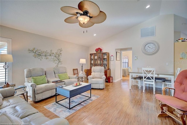 living room with ceiling fan, light wood-type flooring, and vaulted ceiling