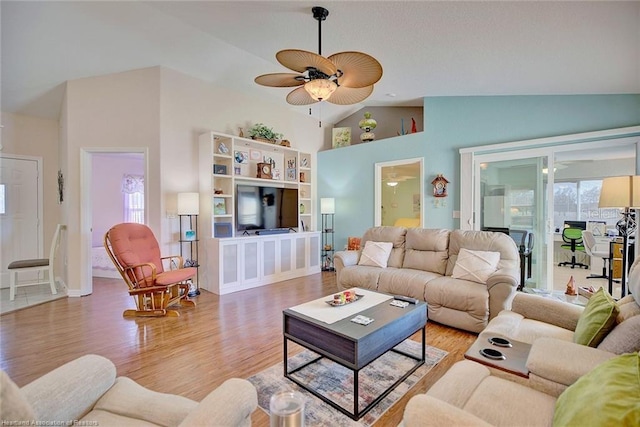 living room with ceiling fan, vaulted ceiling, and light wood-type flooring