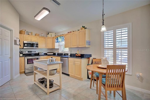 kitchen featuring light brown cabinets, stainless steel appliances, pendant lighting, vaulted ceiling, and light tile patterned floors