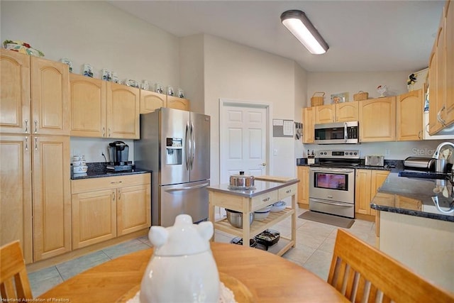 kitchen featuring light tile patterned floors, light brown cabinets, stainless steel appliances, and sink