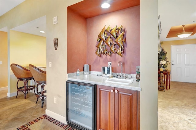 bar with a raised ceiling, light tile patterned floors, sink, and beverage cooler