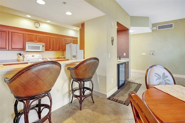 kitchen with white appliances, sink, light tile patterned floors, kitchen peninsula, and beverage cooler