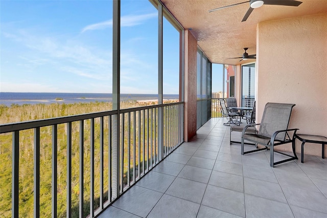 sunroom / solarium with ceiling fan, a water view, and a healthy amount of sunlight