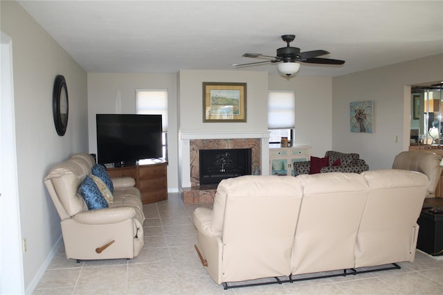 living room featuring ceiling fan, light tile patterned floors, a premium fireplace, and a wealth of natural light