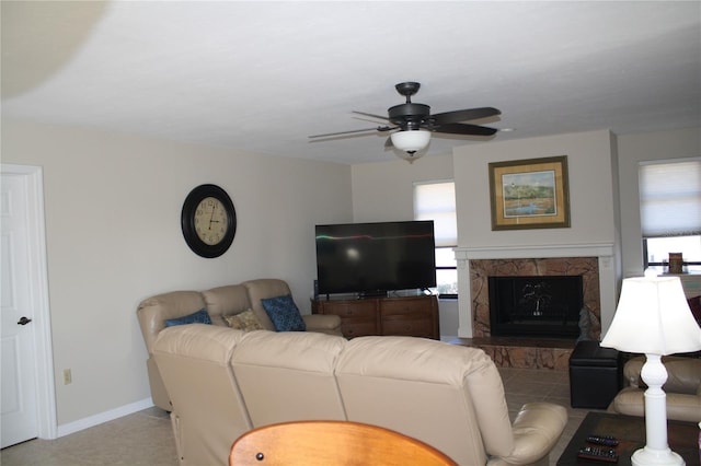 tiled living room featuring ceiling fan and a fireplace