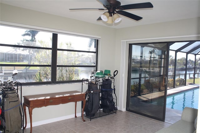 interior space with ceiling fan, a water view, and light tile patterned floors