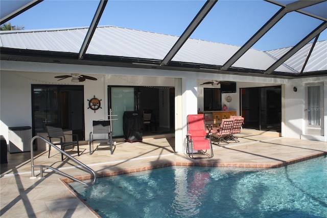 view of pool featuring ceiling fan, a bar, a patio, and glass enclosure