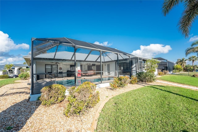 back of property with a lanai, ceiling fan, a lawn, and a fenced in pool