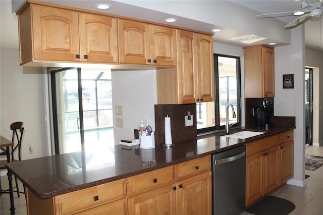 kitchen with dark stone countertops, sink, stainless steel dishwasher, and plenty of natural light