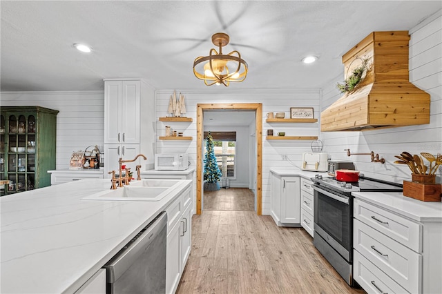 kitchen with stainless steel appliances, wooden walls, and sink