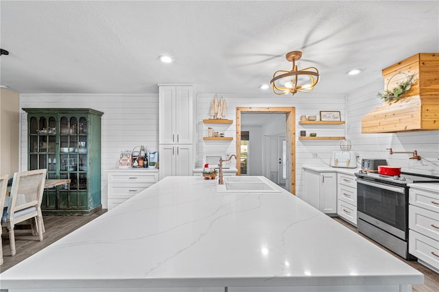 kitchen featuring light stone counters, sink, a center island with sink, hanging light fixtures, and stainless steel electric range