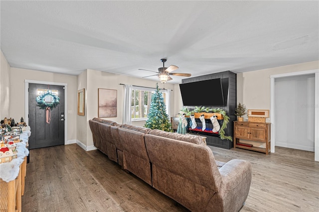 living room with ceiling fan, wood-type flooring, and a textured ceiling