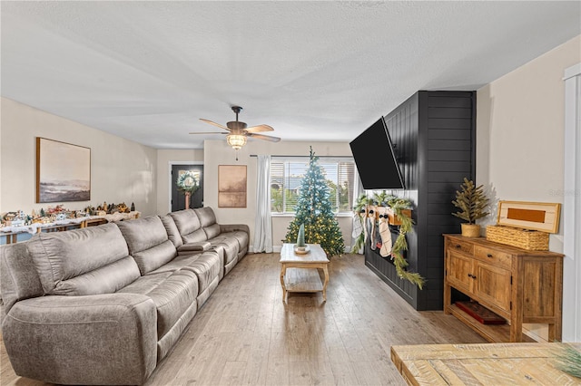 living room with ceiling fan, light hardwood / wood-style flooring, and a textured ceiling