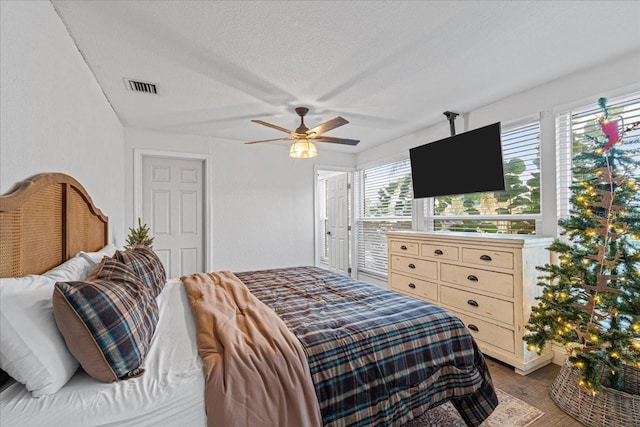 bedroom with hardwood / wood-style floors, ceiling fan, and a textured ceiling