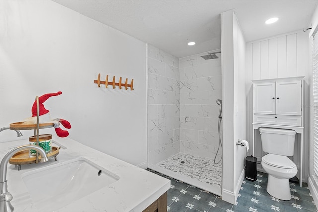 bathroom with a tile shower, vanity, and toilet