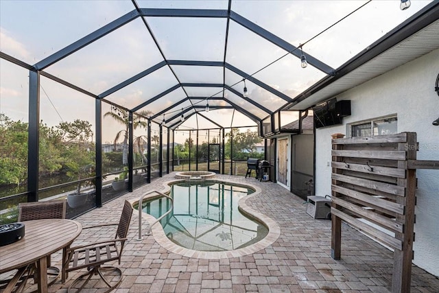 pool at dusk with a lanai, a grill, an in ground hot tub, and a patio