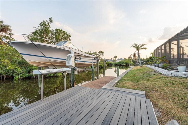 view of dock with a lawn, glass enclosure, and a water view