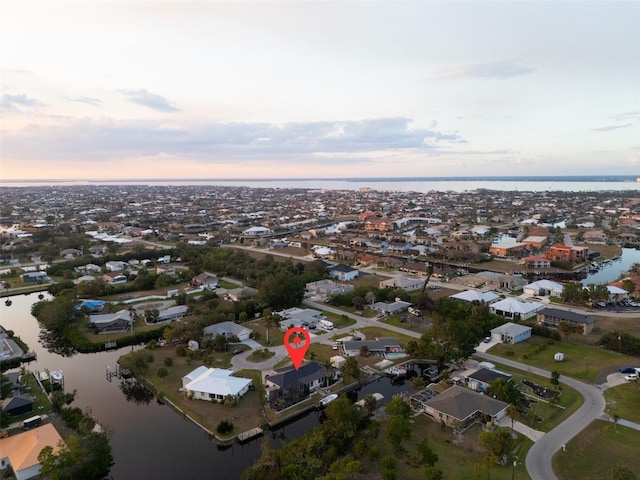 aerial view at dusk featuring a water view