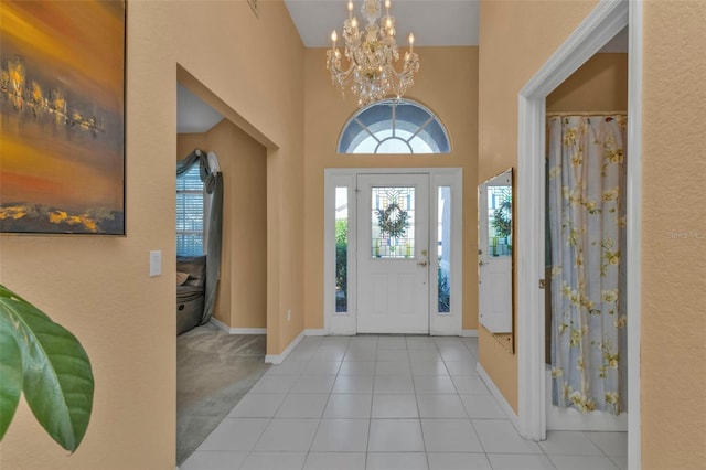 foyer featuring light tile patterned floors, a high ceiling, and a chandelier