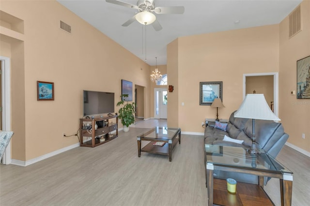 living room with a high ceiling, ceiling fan with notable chandelier, and light hardwood / wood-style floors