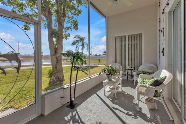 sunroom featuring ceiling fan and a water view