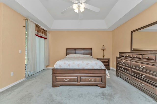 bedroom featuring ceiling fan, light colored carpet, and a tray ceiling