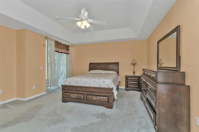 carpeted bedroom with ceiling fan and a tray ceiling