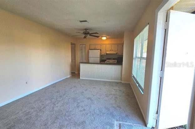 unfurnished living room with light colored carpet and ceiling fan