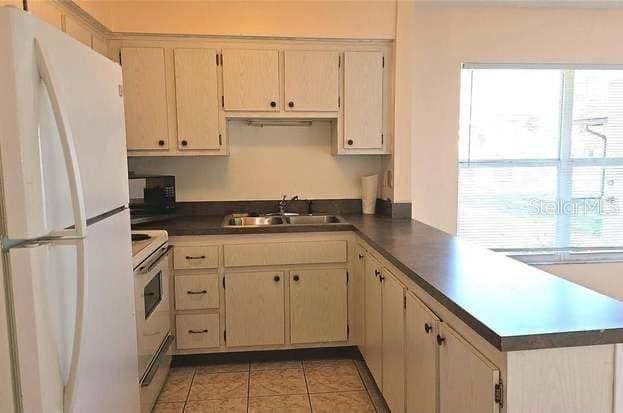 kitchen featuring white appliances, kitchen peninsula, sink, and a wealth of natural light